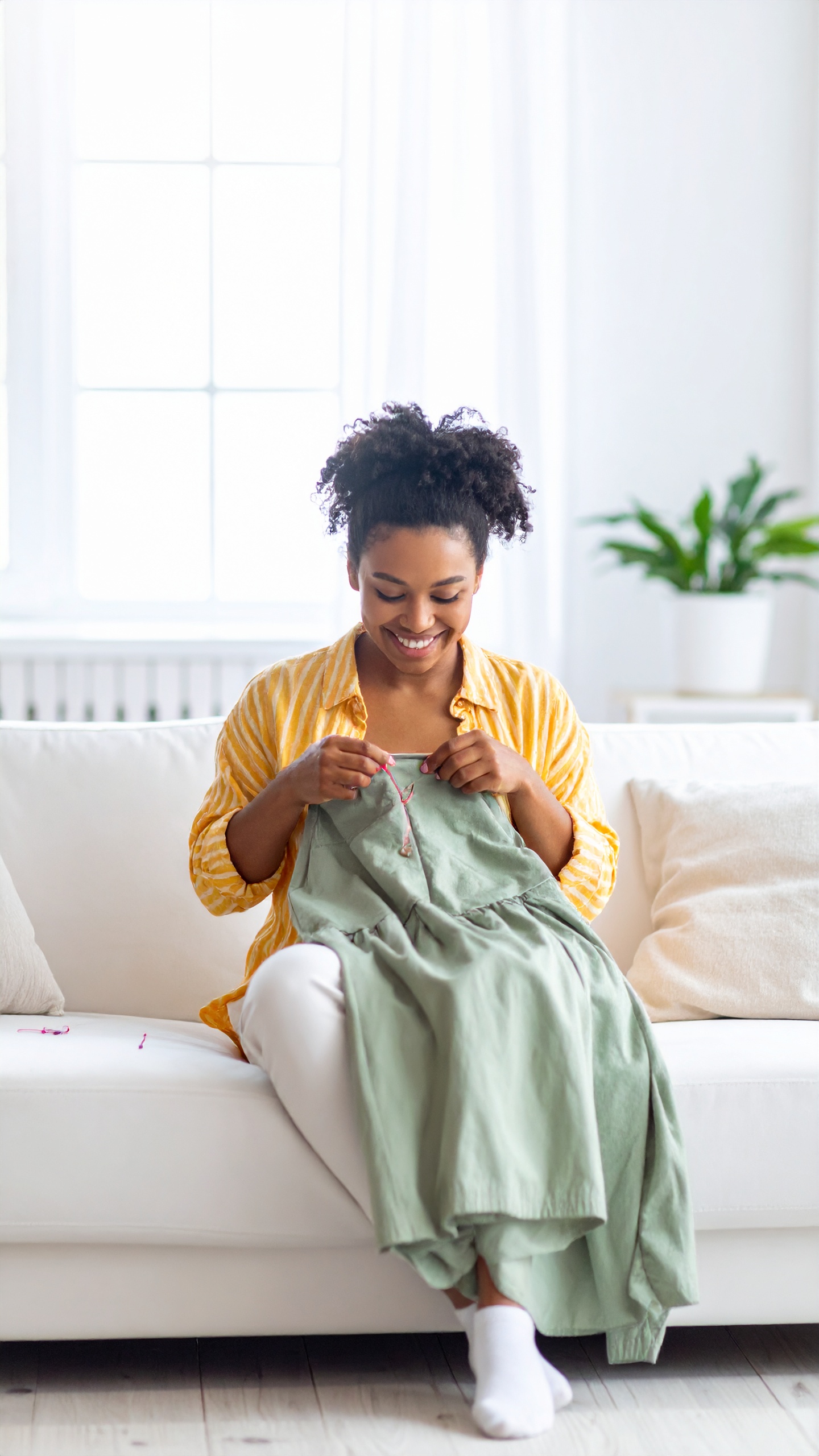 Firefly_Smiling women sitting on sofa sewing dress with needle white room background and indo 465223